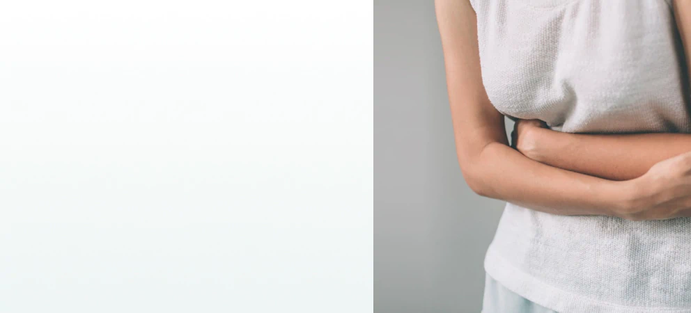 A woman clutching her stomach in discomfort, representing the need for supplements for gut health and digestion.