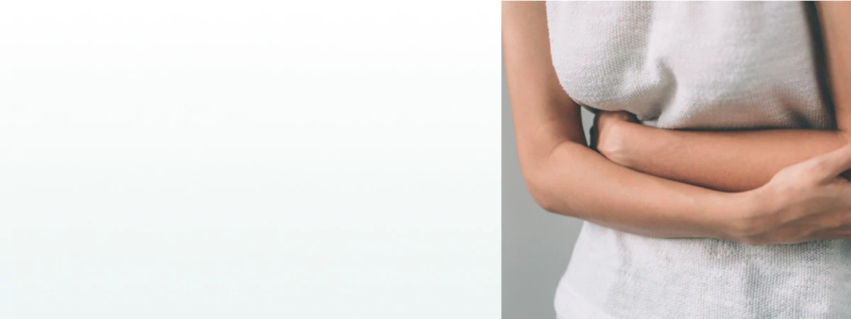 A woman clutching her stomach in discomfort, representing the need for supplements for gut health and digestion.