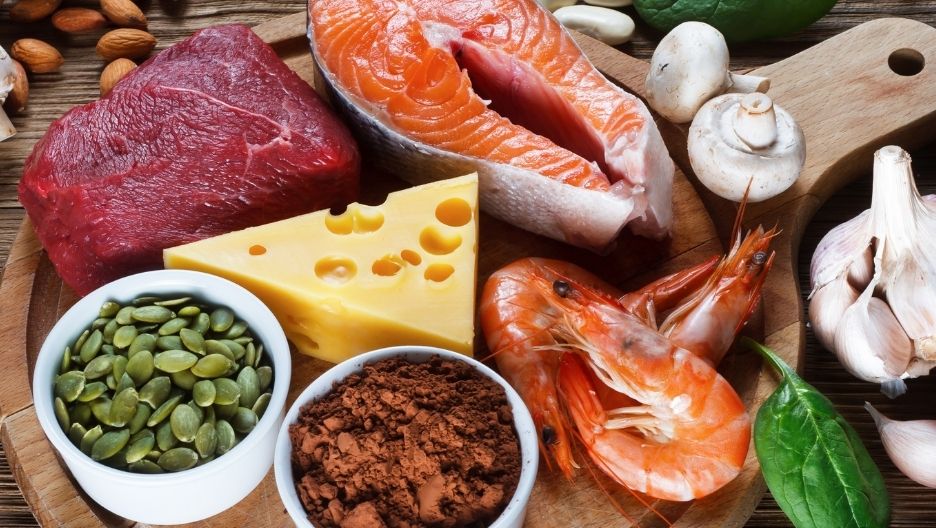 A top-down image displaying a variety of zinc-rich foods, such as beef, shrimp, and pumpkin seeds.